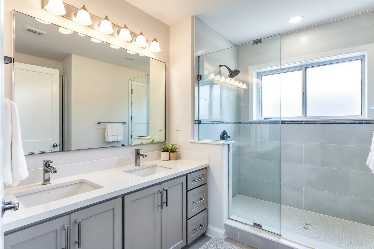 Example ensuite with a grey double vanity, a large glass shower and a frosted window