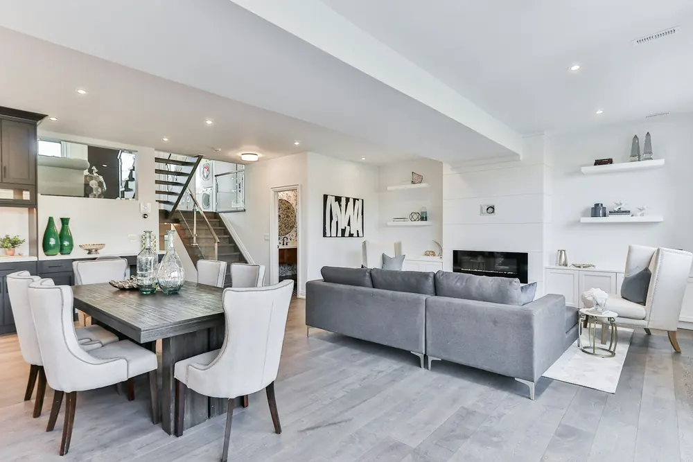 Finished basement with a grey sectional, dining table and media wall