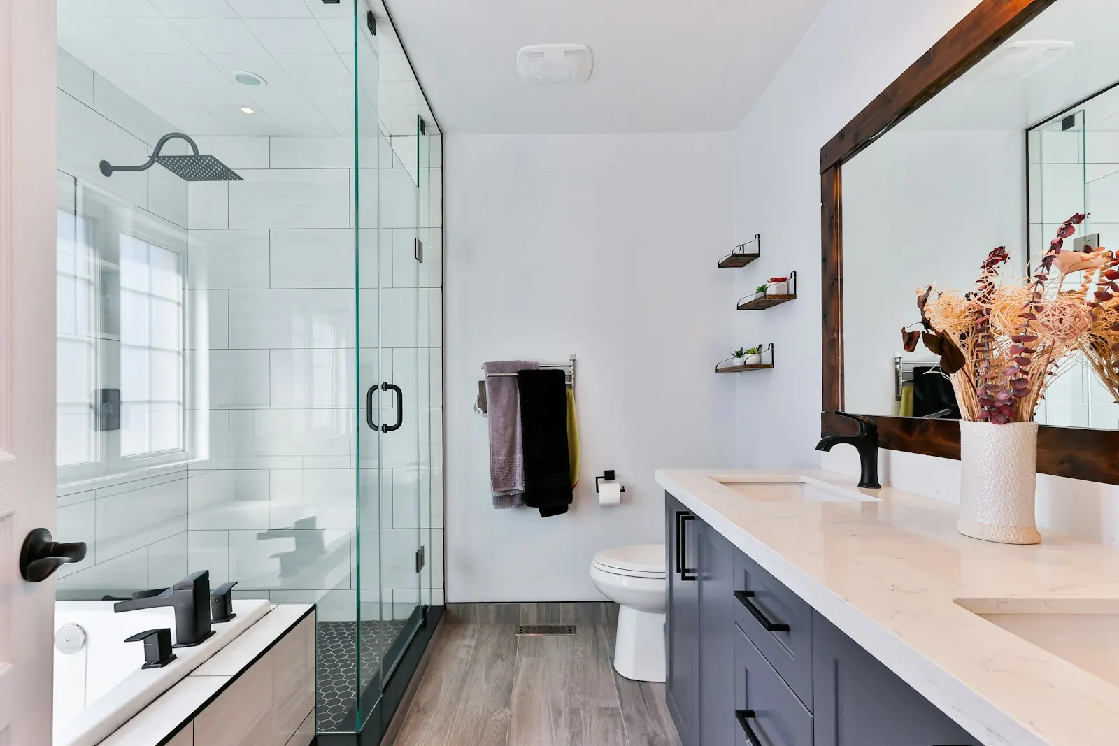 Bathroom with a walk-in glass shower, black fixtures and a wood-look floor
