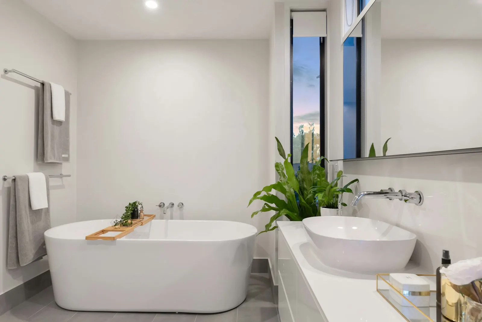 Bright bathroom with a freestanding tub, plants and a round basin