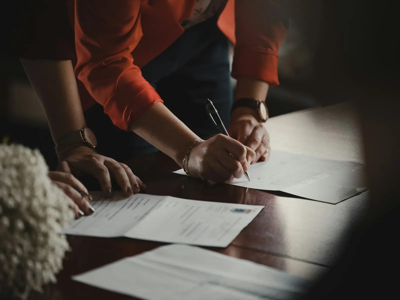 Two people signing a contract at a wooden table