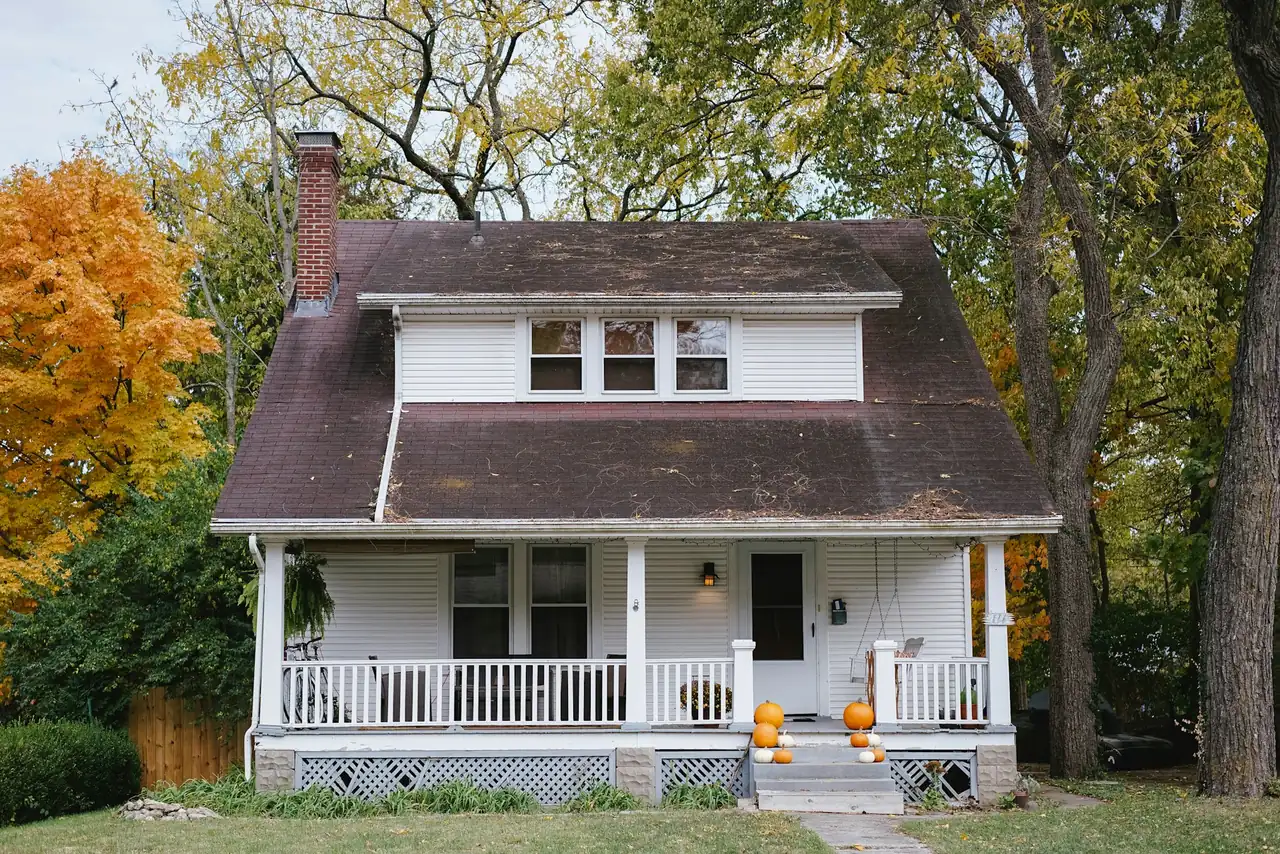 Two-storey house with a white porch and red and orange maple trees