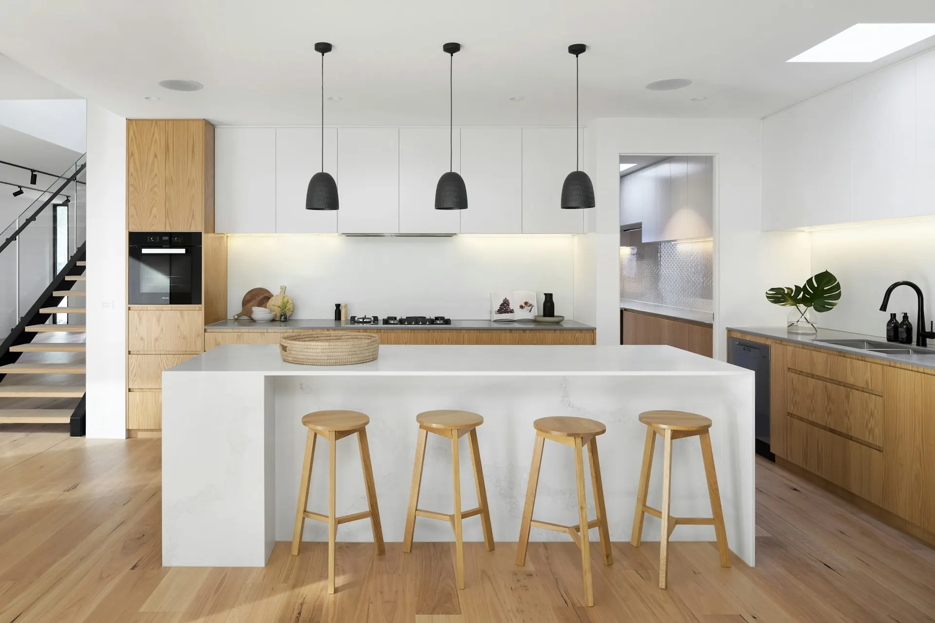 Renovated white kitchen with an island, three wooden stools and pendant lights